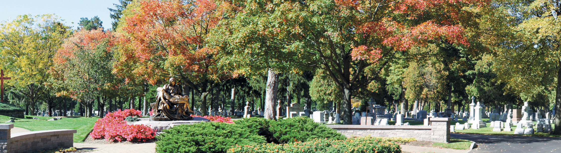 Wide view of a Pieta Monument surrounded by traditional burial areas